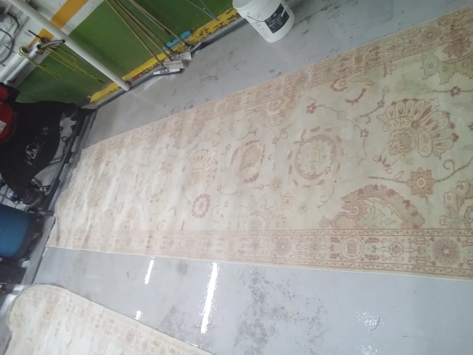 A pale Persian rug spread across the wash floor, in for cleaning from Pinecrest
